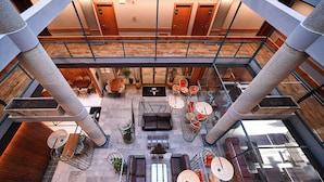 Ein geräumiger Atrium mit hoher Decke, mehreren Sitzbereichen und einer zentralen Treppe.