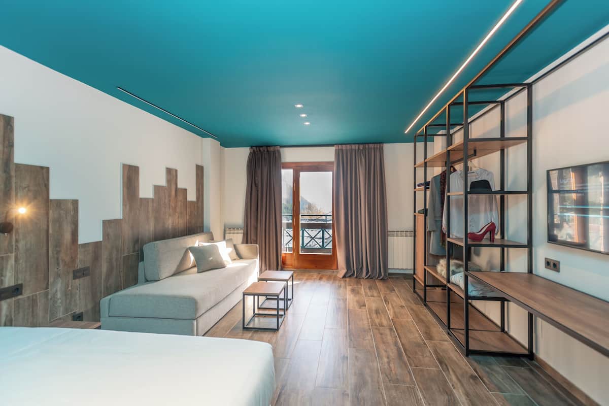 Een moderne hotelkamer met een bed, een bank, een bureau en een kledingkast.