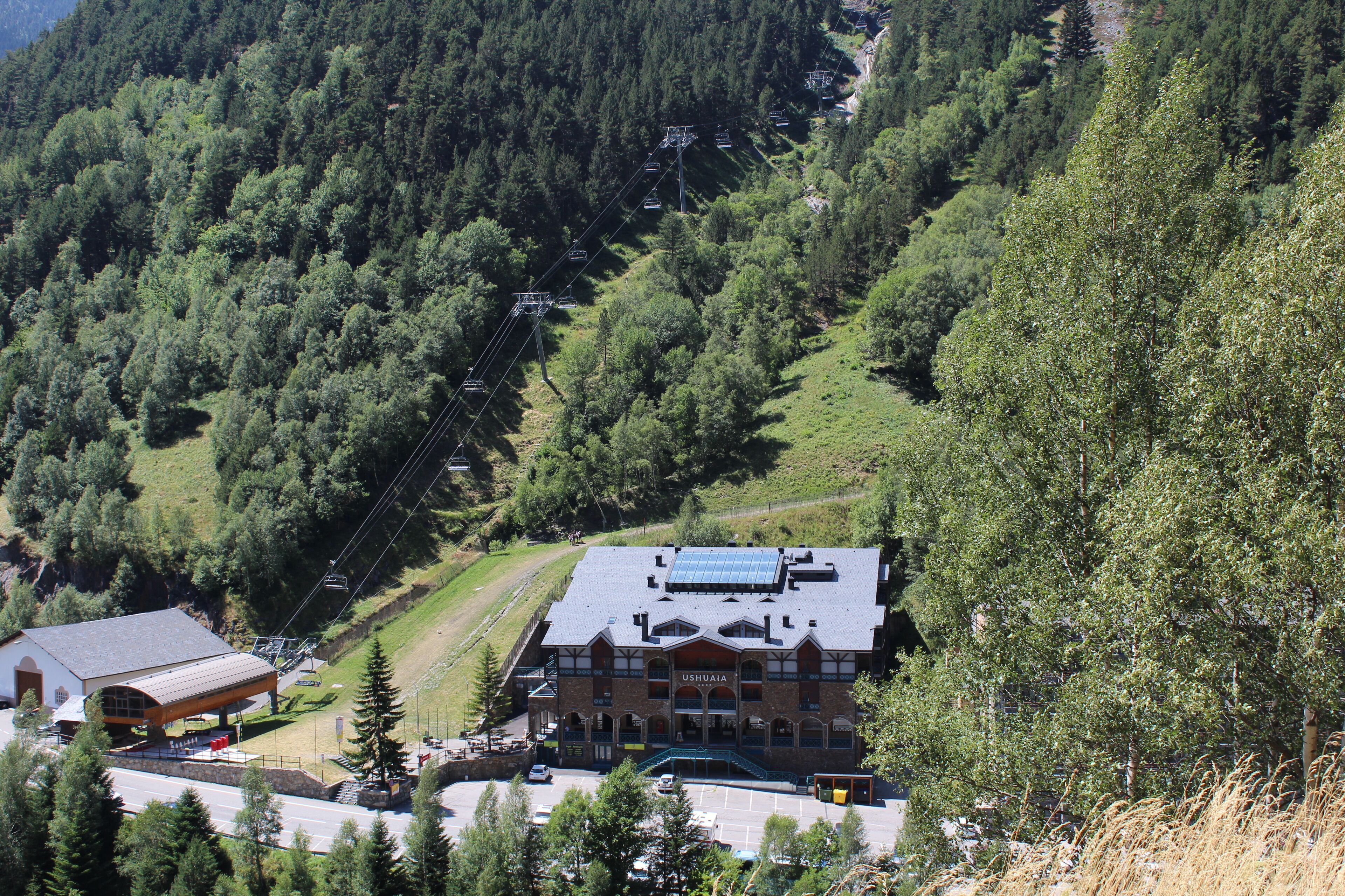 A lodge with a ski lift, surrounded by forested hills.