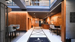 Eine Hotelhalle mit Empfangsschalter, Sitzgelegenheiten und einer Wandgestaltung aus Holz.