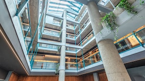 Ein mehrgeschossiges Atrium mit einem offenen Innenbereich, Betonsäulen und Glasgeländern.