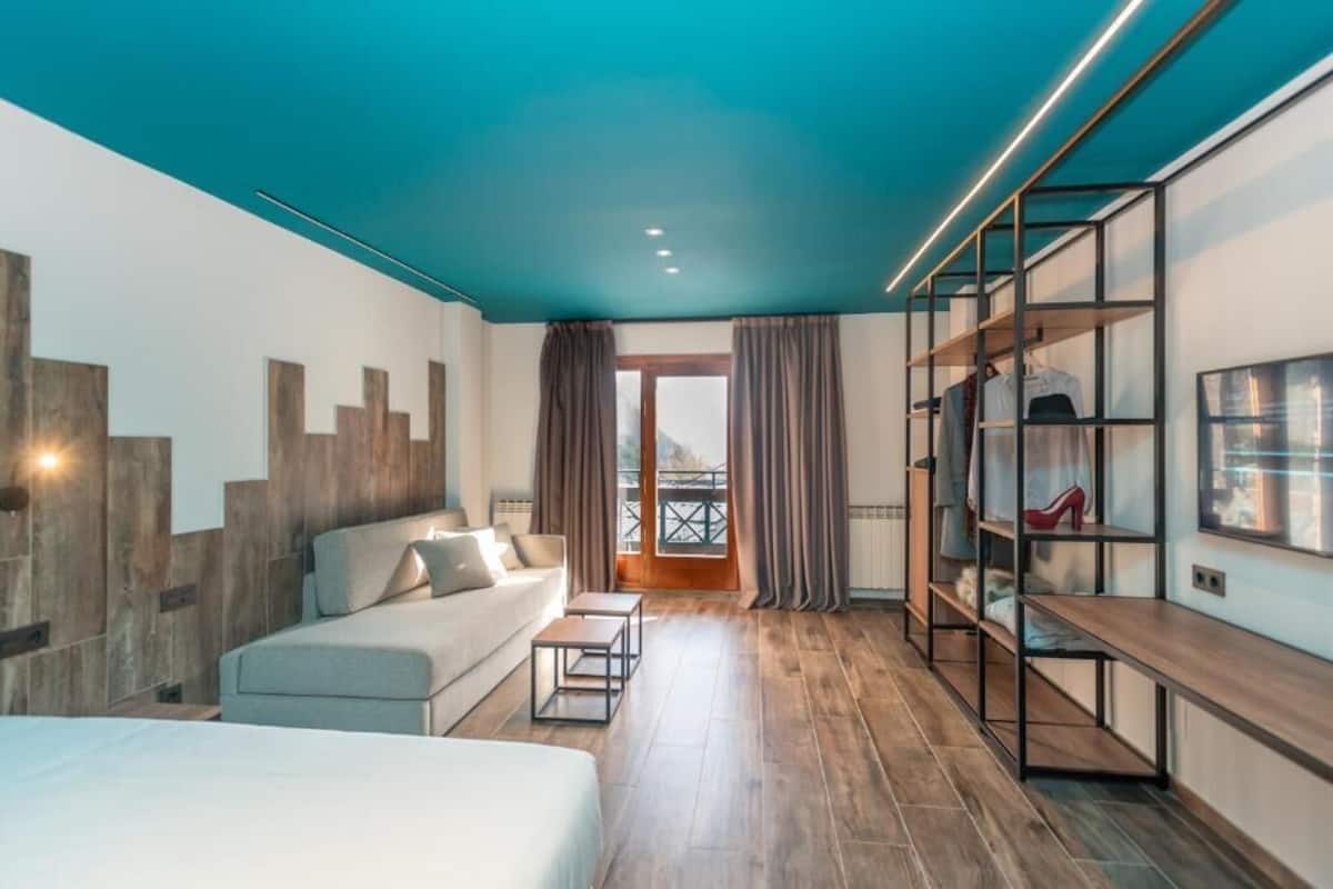Una habitación de hotel moderna con cama, sofá, escritorio y armario.