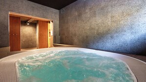 Ein Wellnessbereich mit Whirlpool, Holztüren und einer strukturierten Wand.