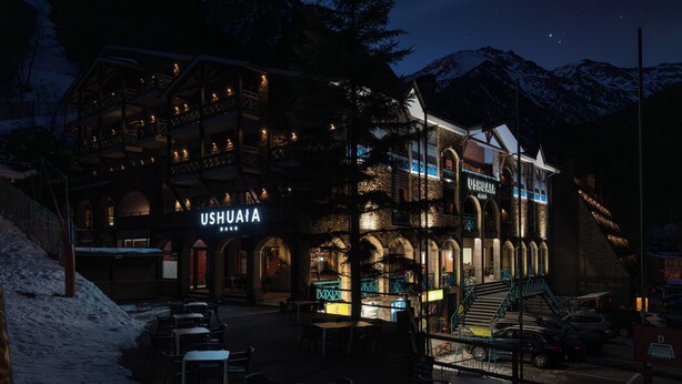 Ein Hotel mit der Aufschrift 'USHUAIYA', nachts beleuchtet, mit einem mehrstöckigen Gebäude, Balkonen und einer Treppe zum Eingang.