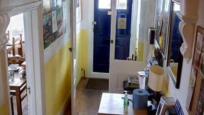 Un pasillo estrecho con un armario de madera, una puerta que da a una habitación y una araña.