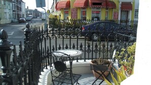 Un patio con una mesa redonda y sillas, rodeado por una valla de hierro decorativa.