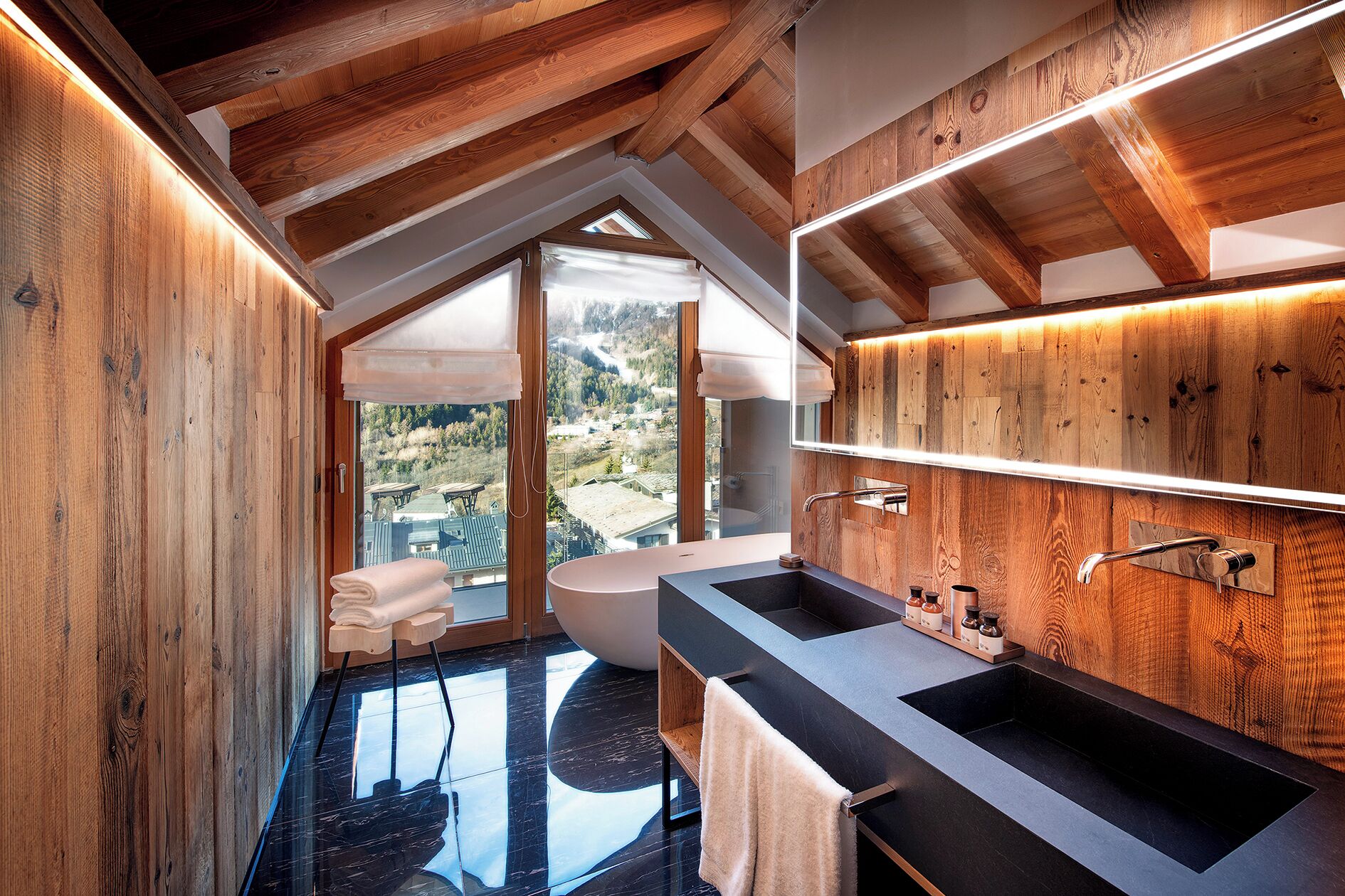 A modern bathroom with wooden beams, a large mirror, and a bathtub.