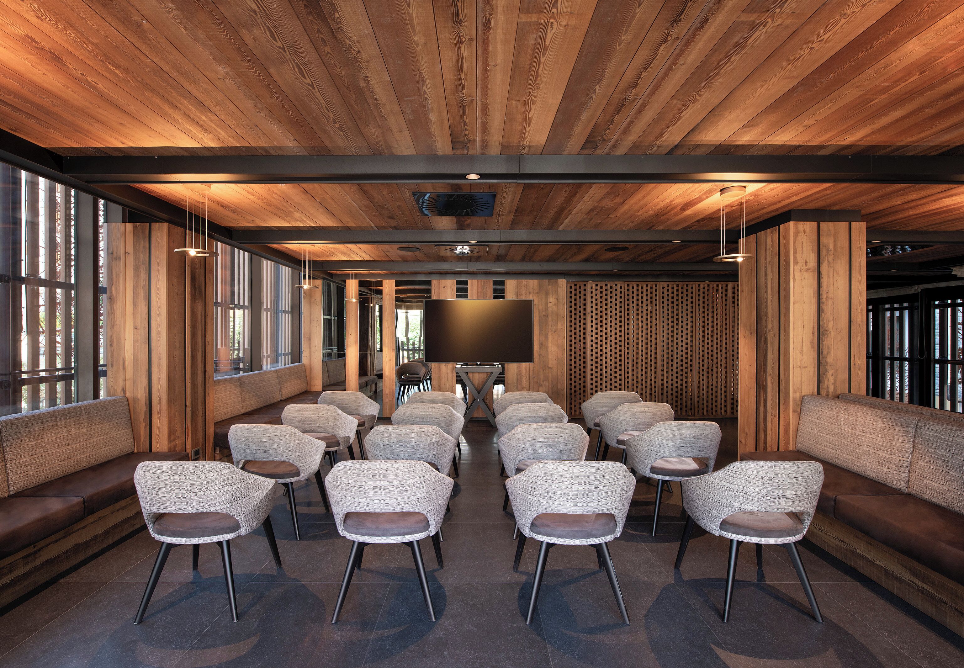 A conference room with a wooden ceiling, large windows, and a flat-screen TV.