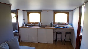 Cocina compacta con un lavamanos, dos taburetes de bar y una ventana sobre la encimera.