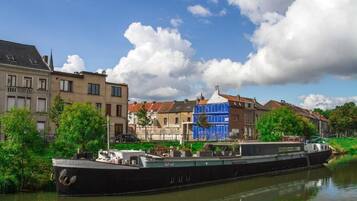 A narrowboat docked by a canal with buildings in the background.