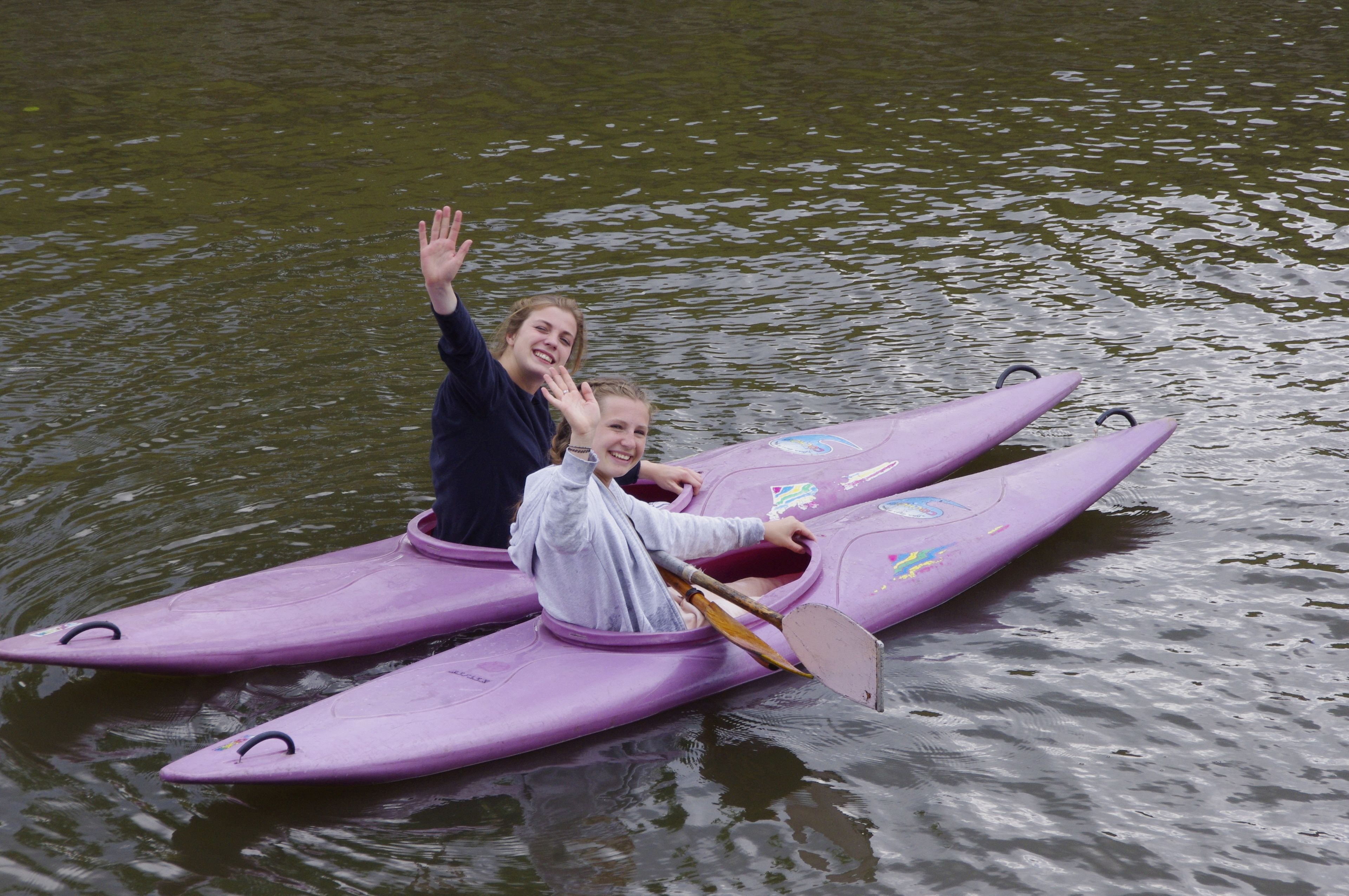 Dos personas en un kayak morado en un cuerpo de agua.