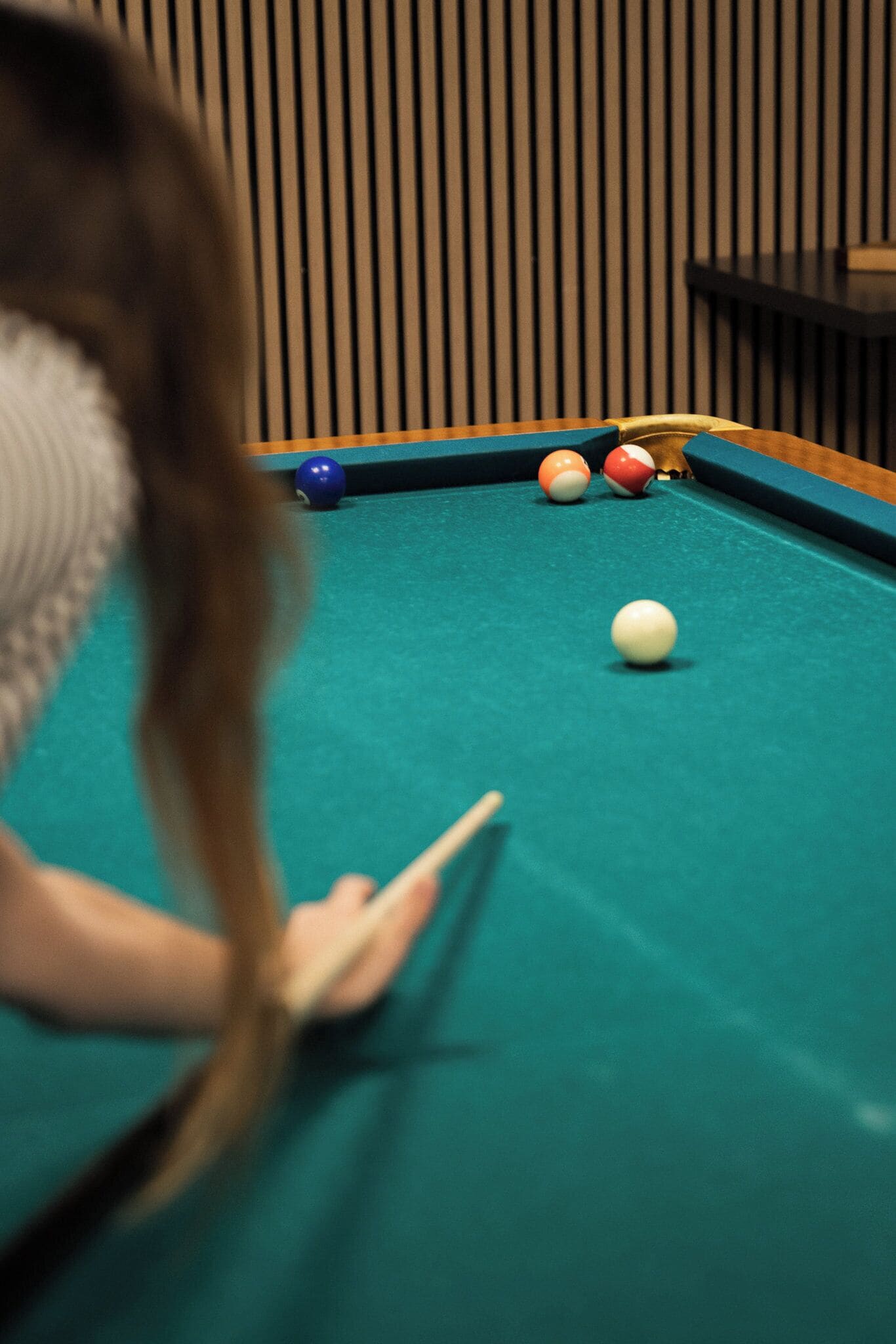 A pool table with balls and a cue stick.