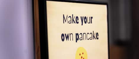 A sign with the text "Make your own pancake" and a smiley face emoji.