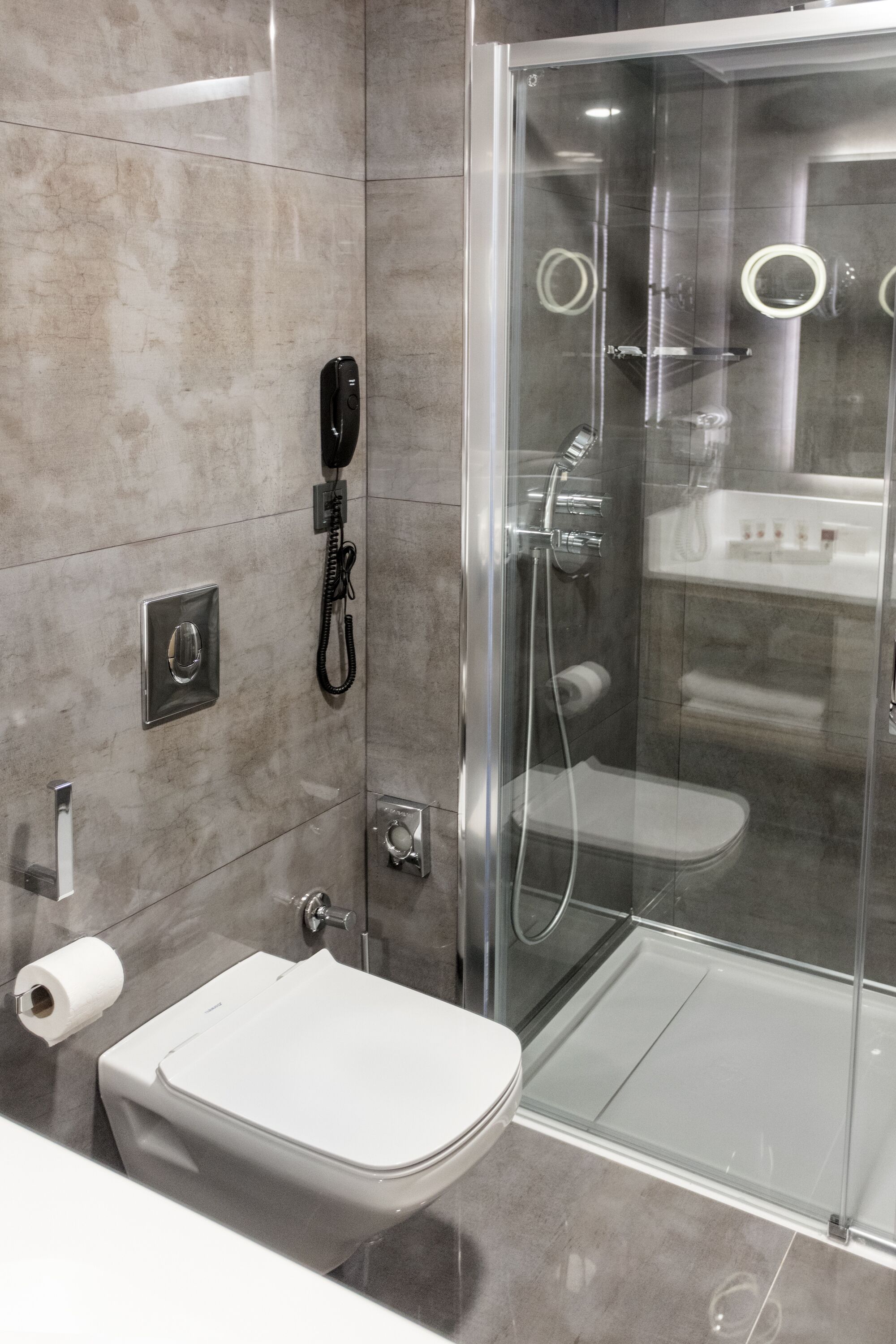 A modern bathroom with a glass-enclosed shower, a toilet, and a sink.