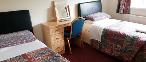 A hotel room with two beds, a desk, and a chair.