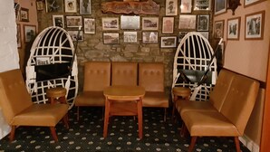 A cozy room with a stone wall, a wooden bench, and two white-framed chairs.