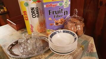 A table with cereal boxes, a jar of sugar, and a tray with glassware.