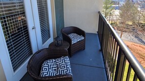 A balcony with wicker furniture and a view of the landscape.