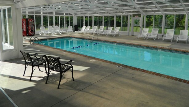 An indoor swimming pool with lounge chairs and a Coca-Cola vending machine.