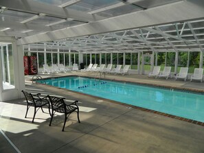 Una piscina interior con sillas de descanso y una máquina expendedora de Coca-Cola.