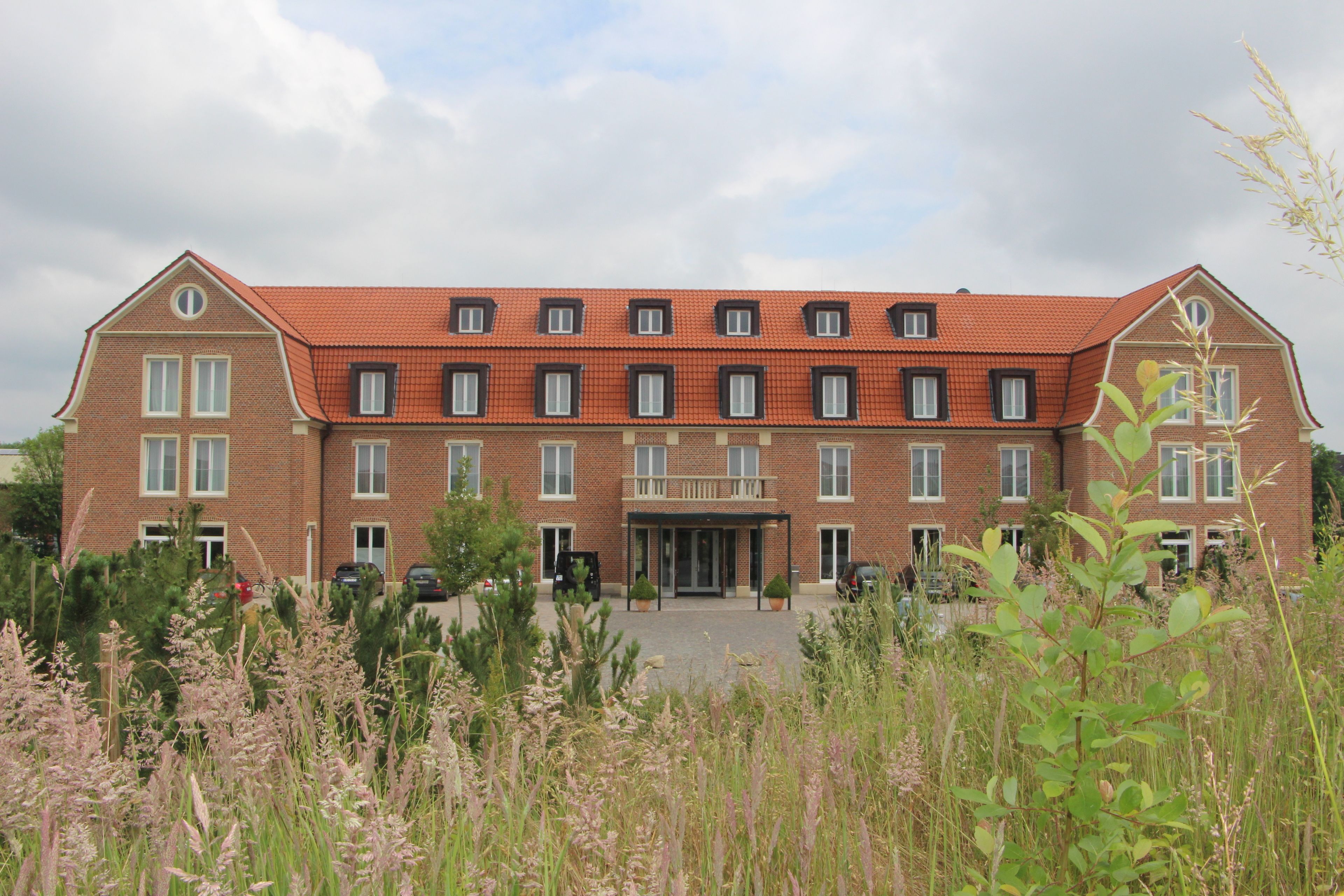 A large brick building with multiple windows and a red-tiled roof.