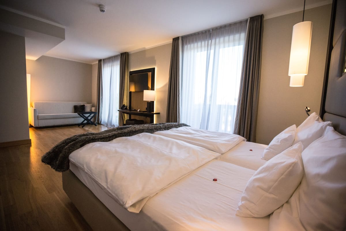 A hotel room with a large bed, a desk, a chair, and a sofa.