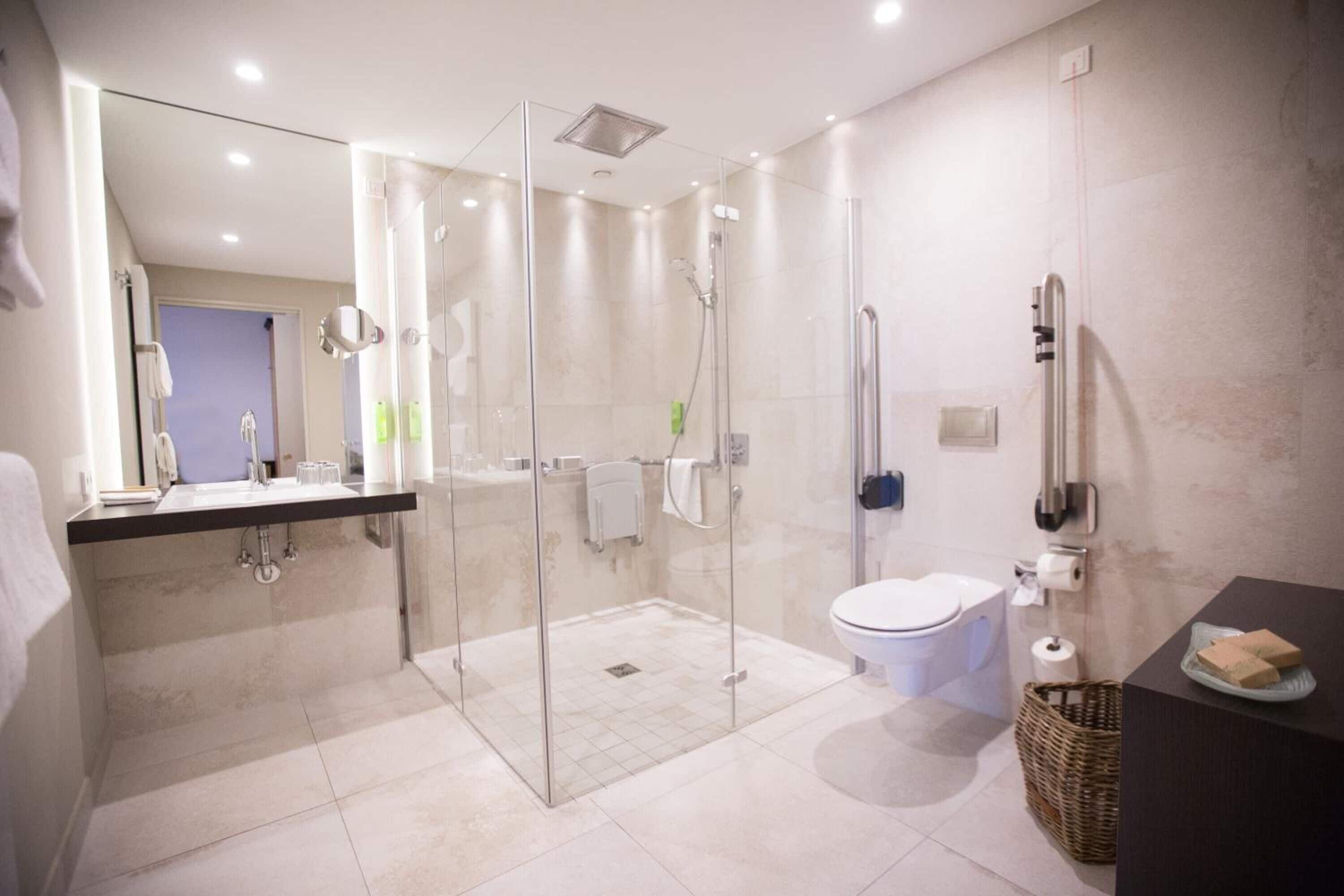 A modern bathroom with a glass-enclosed shower, a toilet, and a sink.