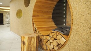A circular wooden structure with a seating area and a log pile inside. - Hofhotel Grothues-Potthoff (Senden)