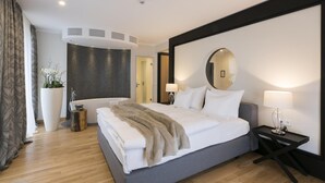 A modern hotel room with a large bed, a bedside table, a mirror, and a potted plant. - Hofhotel Grothues-Potthoff (Senden)
