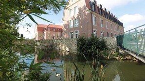 A traditional brick building with a stone wall and a small pond with ducks. - Hofhotel Grothues-Potthoff (Senden)