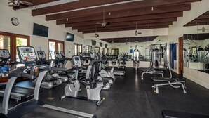 Un gimnasio con cintas de correr, elípticas y equipo de pesas.