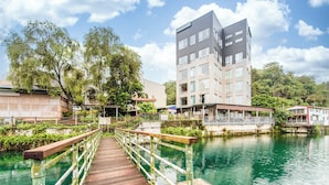 A wooden bridge over a calm river, leading to a modern building with multiple floors and balconies. - Shui Yang Lakeview House with Elevator (Yuchi)