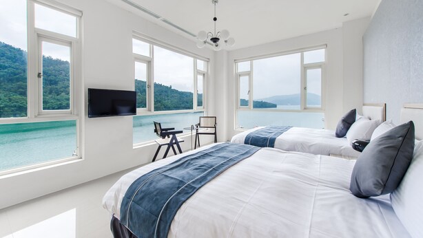 A bedroom with two beds, a TV, and a view of a lake and mountains. - Shui Yang Lakeview House with Elevator (Yuchi)