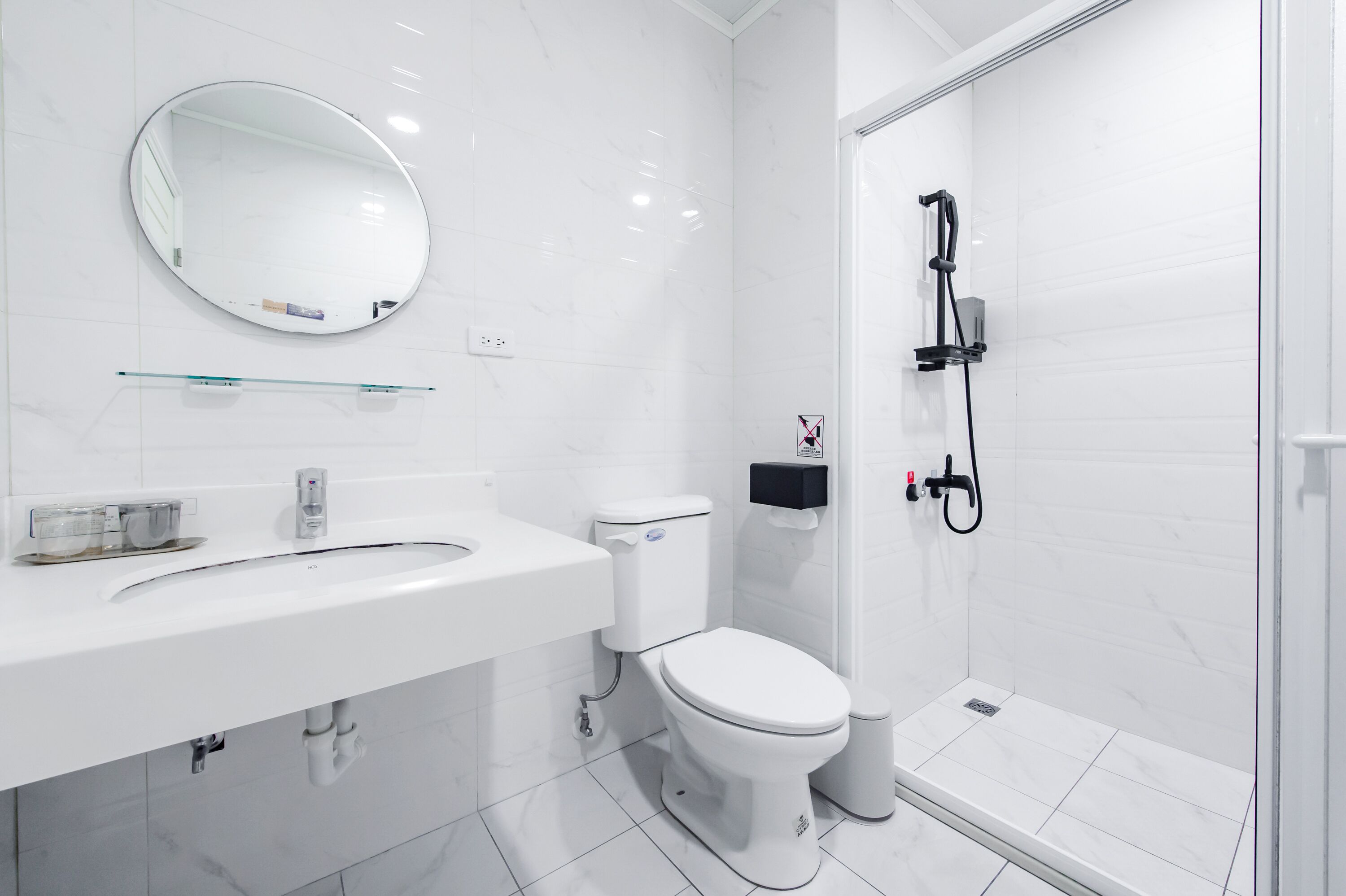 A modern bathroom with a white sink, toilet, and shower.