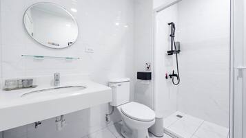 A modern bathroom with a white sink, toilet, and shower.