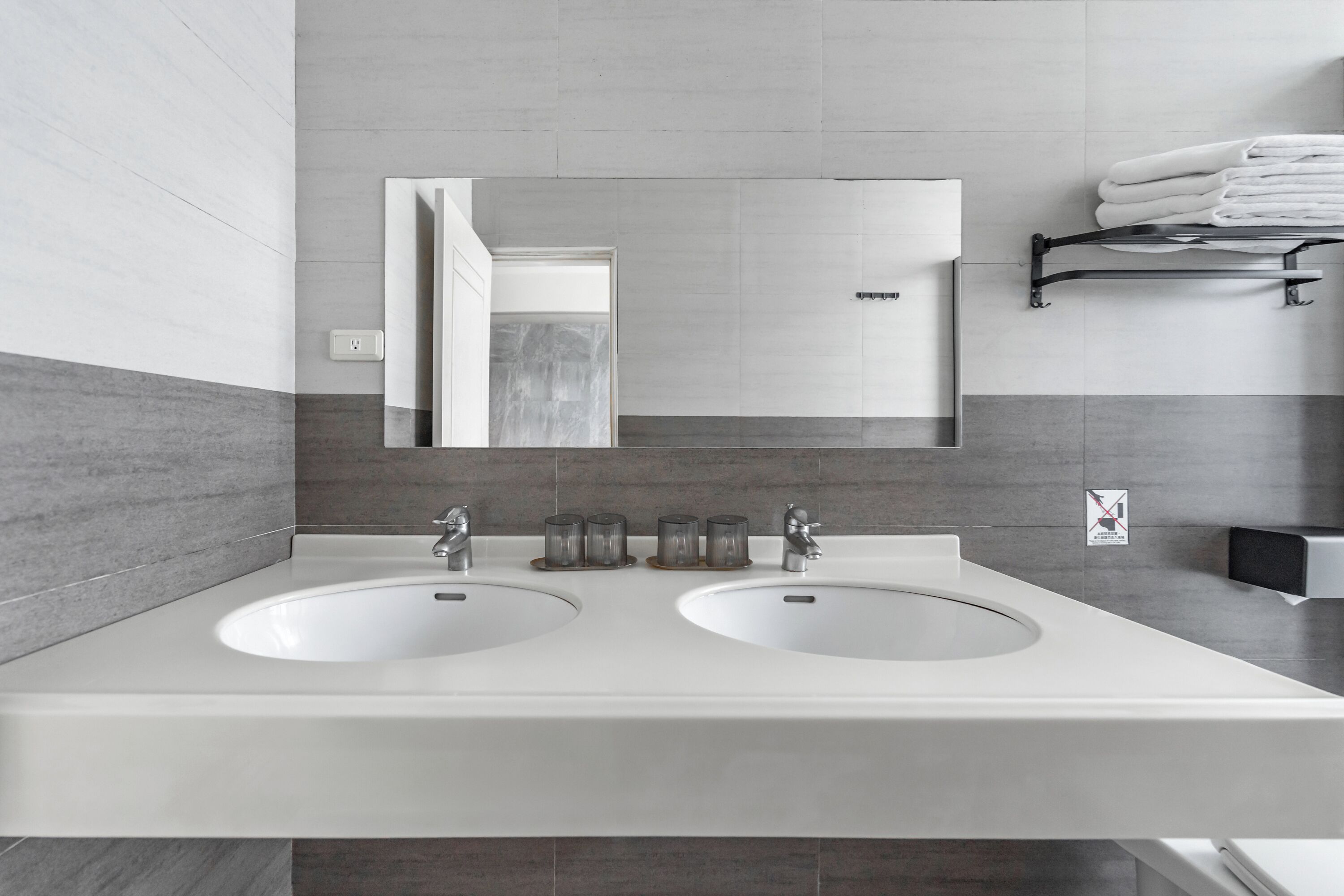 A modern bathroom with two sinks, a mirror, and a towel rack.