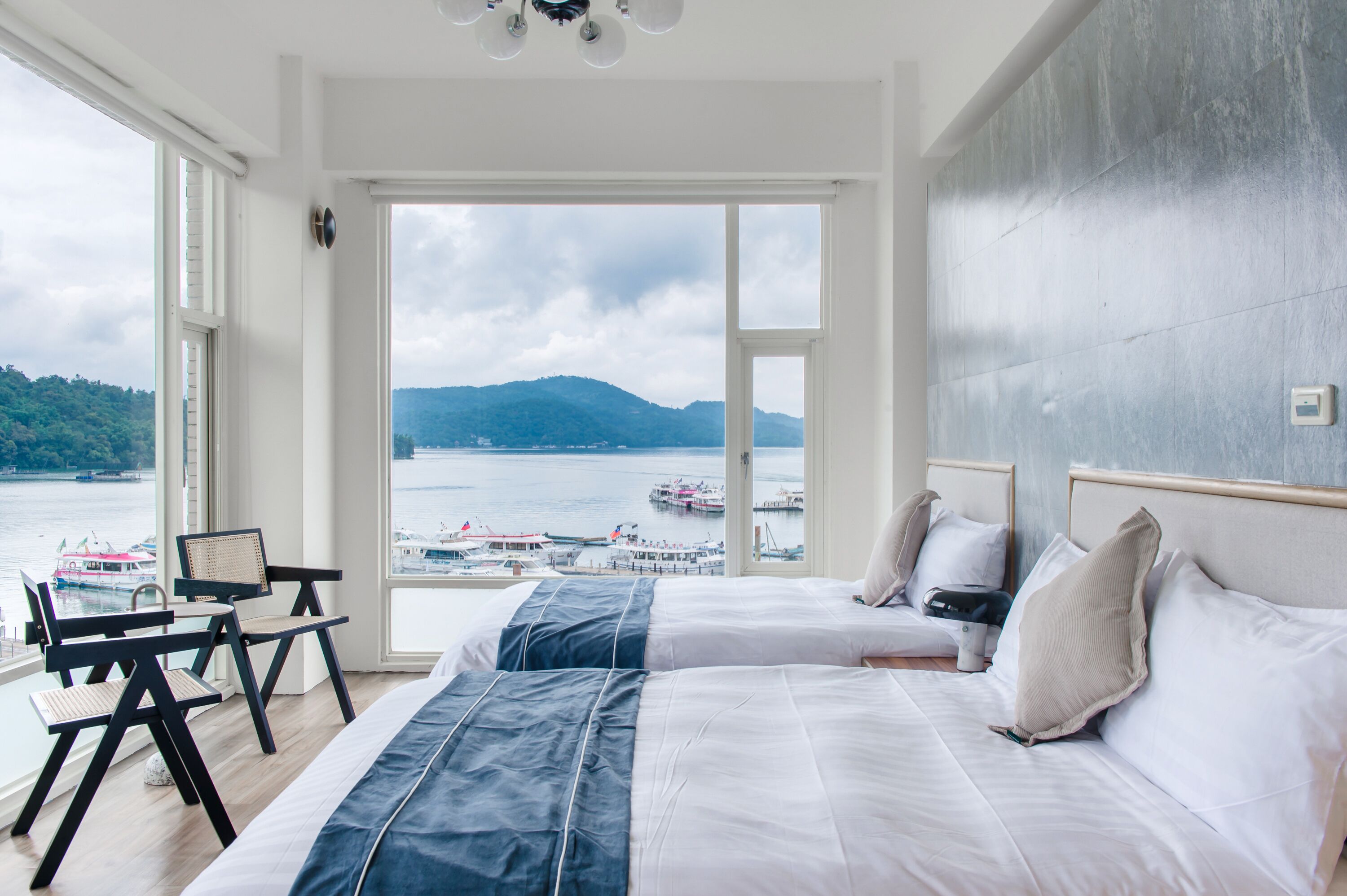Habitación de hotel con dos camas, vistas al mar y una zona de comedor con mesa y sillas.