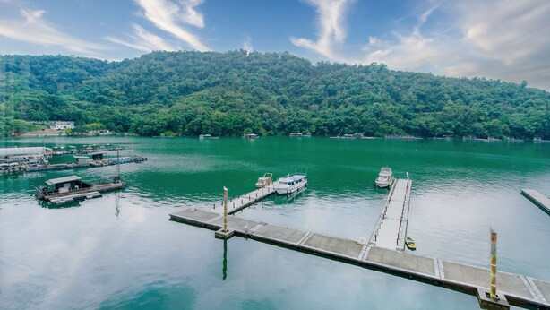 A calm lake with boats docked at a pier, surrounded by lush green hills. - Shui Yang Lakeview House with Elevator (Yuchi)