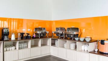 A buffet setup with multiple serving stations, a coffee machine, and various dishes and utensils.