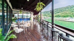 A covered outdoor seating area with tables and chairs, overlooking a body of water and a hilly landscape. - Shui Yang Lakeview House with Elevator (Yuchi)
