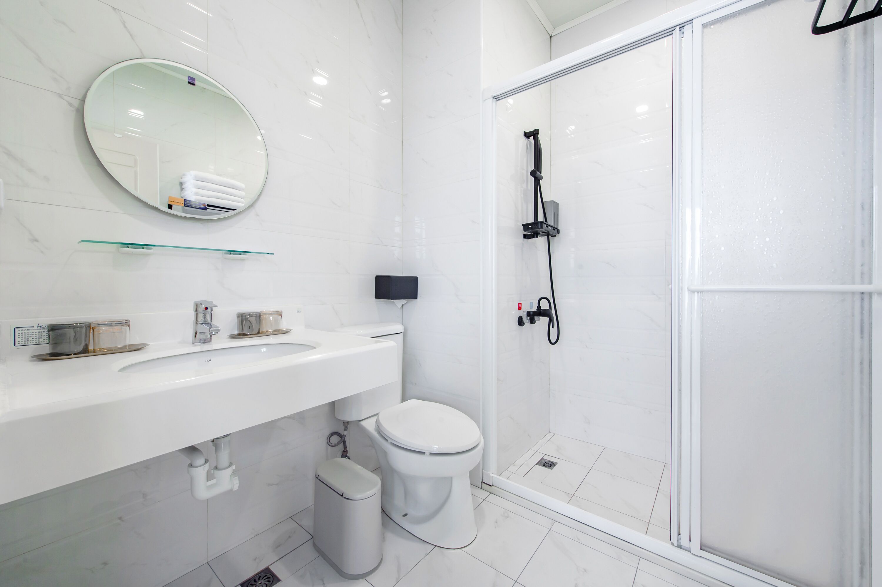 Un baño moderno con lavamanos, inodoro y ducha blancos.