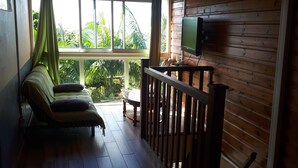 A wooden-floored balcony with a sofa and a TV.