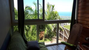 A room with a large window overlooking a lush landscape and the ocean.