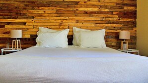 A bed with white linens and pillows, flanked by two bedside tables with lamps, against a wooden wall. - Casa do Salgueiral Douro (Peso da Régua)
