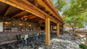 Une terrasse extérieure avec un sol en pierre, des poutres en bois et un mur en pierre.