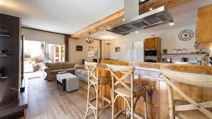 Une cuisine moderne agrémentée d’éléments en bois, un coin bar avec des tabourets et une table à manger.