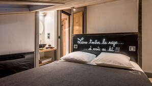 A bedroom with a bed, a bedside table, a mirror, and a blackboard with text.