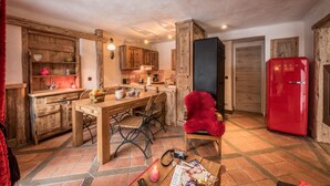 A rustic kitchen with wooden cabinets, a dining table, and a red refrigerator.