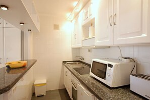 A compact kitchen with white cabinets, a microwave, a toaster, and a small trash bin. - Coronado U 25 (Marbella)