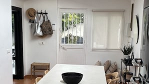 Ein Essbereich mit einem weißen Tisch, Holzstühlen, einer schwarzen Schüssel und einem gemusterten Teppich.